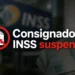 Aviso de suspensão do consignado INSS com notas de real ao fundo desfocado