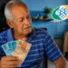 Idoso segurando dinheiro em casa, com logo da Previdência Social ao lado, representando alerta sobre mudanças no calendário da segunda parcela do 13º salário do INSS