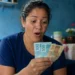 Mulher segurando notas de dinheiro representando o depósito de novo lote do auxílio de R$ 7.300 pela CAIXA.