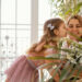Menina beijando a mãe no rosto enquanto entrega um buquê de flores brancas