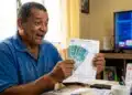 Segurado do INSS segurando dinheiro e extrato de pagamento, em referência à liberação de benefícios de R$ 8.475,55 e valor extra em junho
