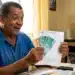 Segurado do INSS segurando dinheiro e extrato de pagamento, em referência à liberação de benefícios de R$ 8.475,55 e valor extra em junho