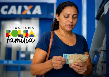 Mulher conferindo notas de dinheiro em caixa eletrônico da Caixa, representando beneficiários do Bolsa Família com NIS final 3 que recebem pagamento de R$ 850 nesta quarta-feira (20).