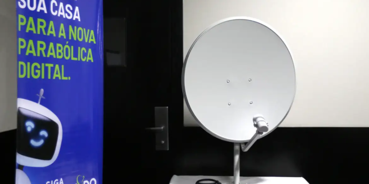 Kit da nova parabólica digital exposto ao lado do banner da campanha Siga Antenado da Anatel sobre a troca de antenas