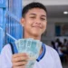 Estudante de escola pública segurando notas de R$ 100 em ambiente escolar representa o pagamento do Pé-de-Meia de R$ 200 e R$ 225 em maio.