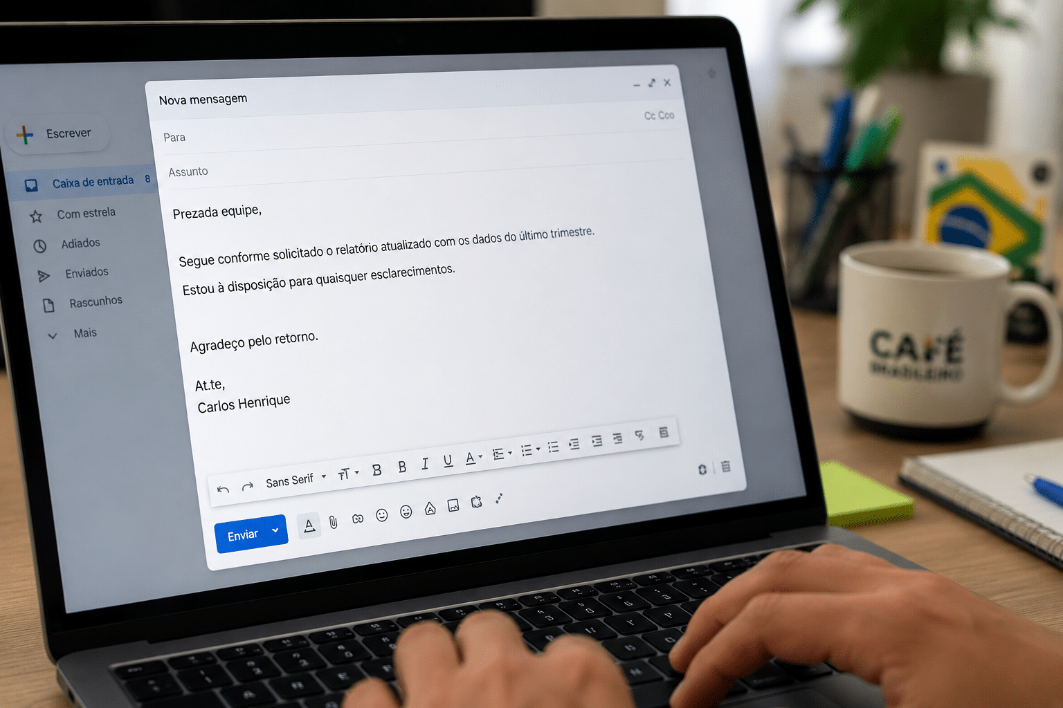 Mãos digitando em laptop com e-mail do Gmail aberto, mensagem formal assinada por Carlos Henrique sobre relatório trimestral.