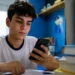 Estudante consulta o celular enquanto estuda, representando a busca de informações sobre o valor e o prazo de pagamento da taxa do Enem 2026.