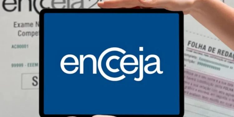 Mãos segurando tablet com logotipo do Encceja em destaque sobre cartão de prova e folha de redação