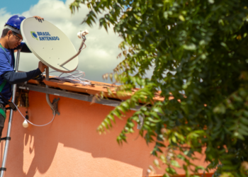 Técnico instala antena parabólica digital Brasil Antenado no telhado de casa residencial