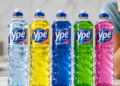 Cinco frascos de detergente Ypê nas cores azul claro, amarelo, azul escuro, verde e rosa alinhados sobre bancada.