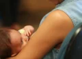Mãe segura bebê recém-nascido no colo, representando o desafio de conciliar a maternidade com a vida profissional