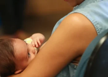 Mãe segura bebê recém-nascido no colo, representando o desafio de conciliar a maternidade com a vida profissional