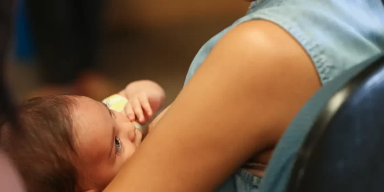 Mãe segura bebê recém-nascido no colo, representando o desafio de conciliar a maternidade com a vida profissional