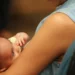 Mãe segura bebê recém-nascido no colo, representando o desafio de conciliar a maternidade com a vida profissional