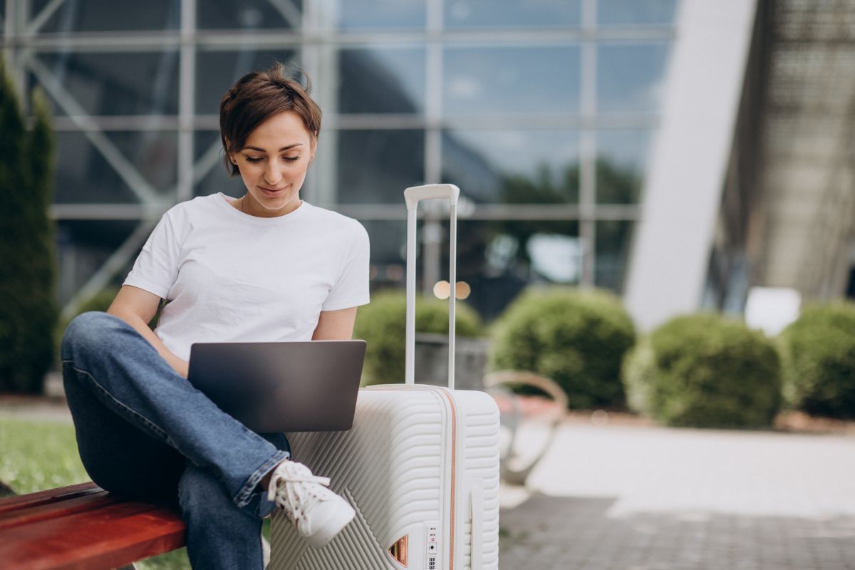 Mulher trabalha em um notebook ao ar livre, representando a flexibilidade de profissões que permitem atuação remota