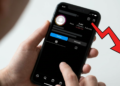 Mão segurando smartphone com perfil do Instagram mostrando 2,4M seguidores e alerta de 150K lost em vermelho.