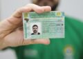 Homem exibindo a Carteira Nacional de Habilitação brasileira em destaque para a câmera