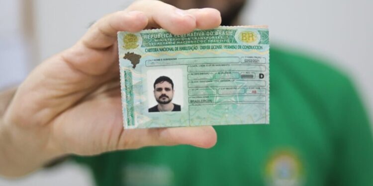 Homem exibindo a Carteira Nacional de Habilitação brasileira em destaque para a câmera