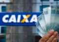 Notas de R$ 100 em frente a uma agência da Caixa, ilustrando saque de R$ 6.220 com prazo de solicitação em maio para alguns CPFs.