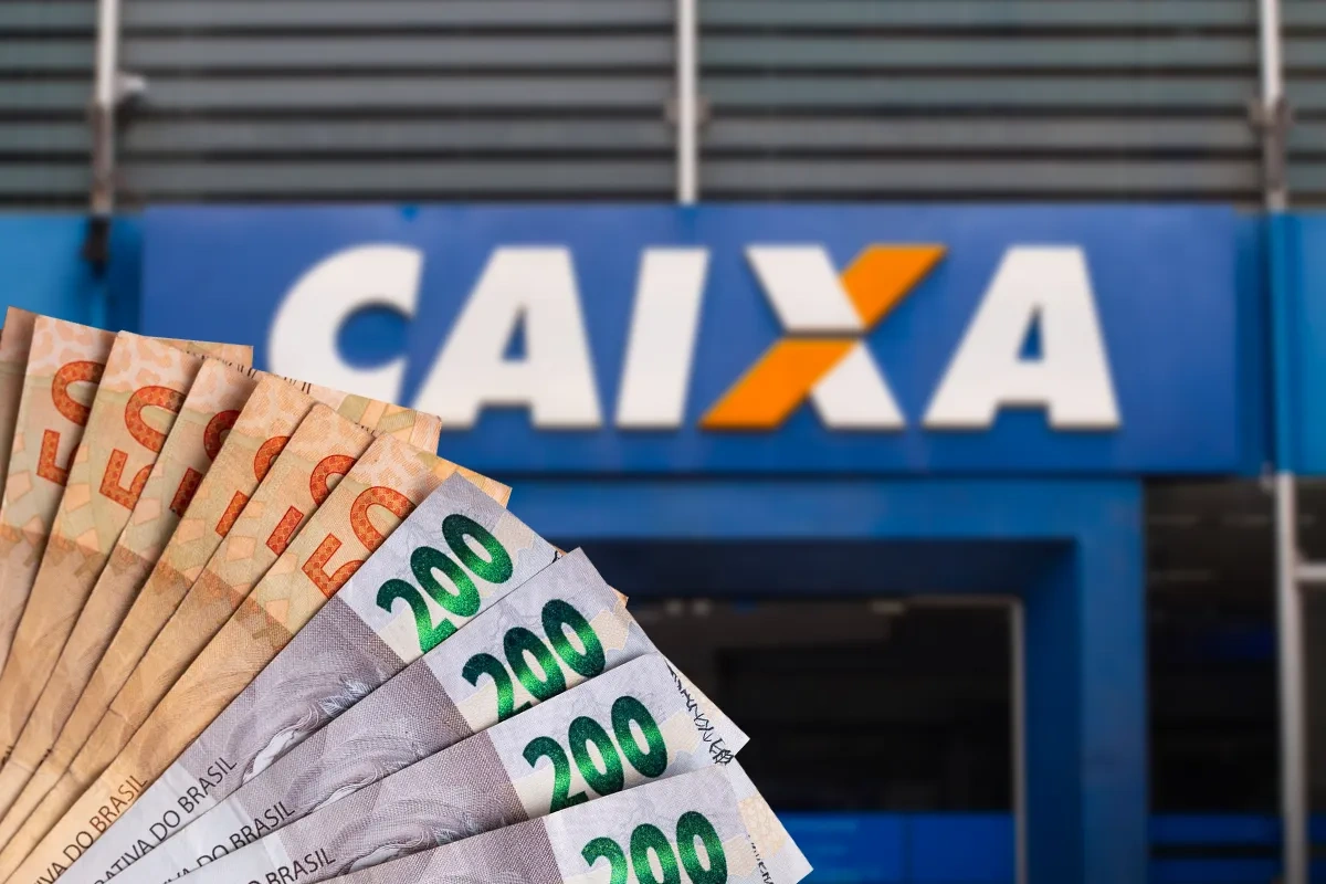 Cédulas de reais em frente a uma agência da Caixa ilustram o saque de até R$ 6.220 do Saque Calamidade do FGTS.