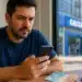Homem mexendo no celular, representando o processo de solicitação do saque de R$ 6.220 da CAIXA até domingo (24).