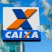 Logo da CAIXA em destaque com notas de R$ 100 ao fundo, ilustrando saque de R$ 6.220 para moradores da Bahia e Minas Gerais.