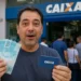 Homem segurando dinheiro e cartão da Caixa em frente à agência, representando o saque de R$ 2.900 liberado para CPFs com finais de 0 a 9.