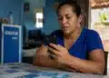 Mulher mexendo no celular, representando a solicitação do saque de R$ 6.220 pela CAIXA.