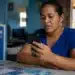Mulher mexendo no celular, representando a solicitação do saque de R$ 6.220 pela CAIXA.