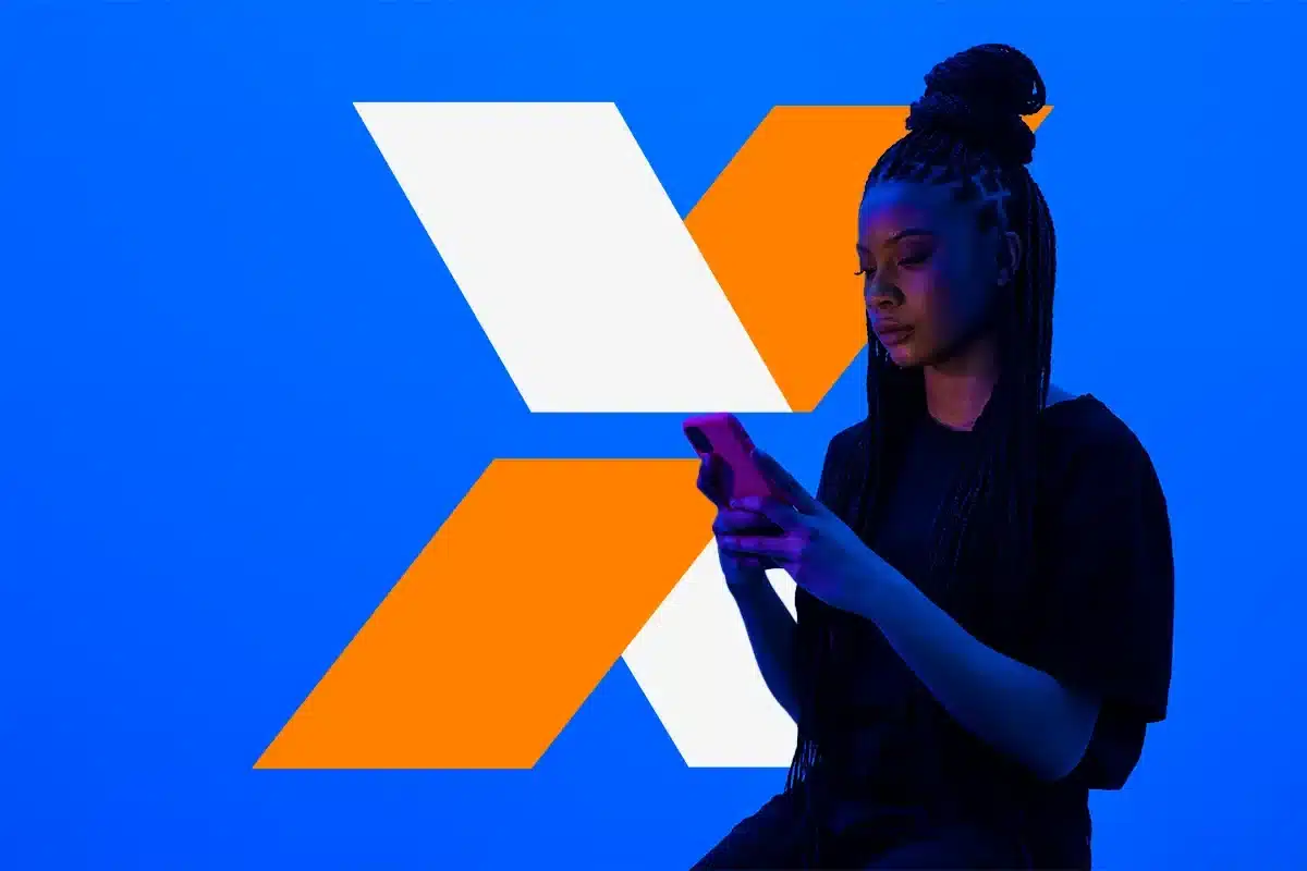 Mulher usando celular diante de fundo com identidade visual da Caixa, representando o pedido do Saque Calamidade do FGTS de até R$ 6.220 até sábado, 30 de maio.