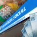 Fachada azul da Previdência Social com logotipo do INSS e notas de R$ 100 e R$ 50 representando o pagamento do 13º salário