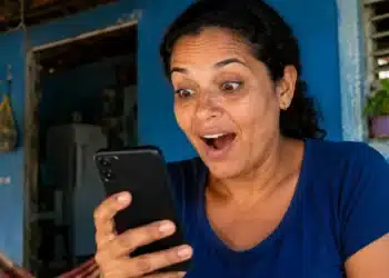 Mulher mexendo no celular com expressão de surpresa, representando a solicitação do saque de R$ 6.220 pelo aplicativo do FGTS.