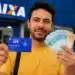 Homem segurando CPF e dinheiro em frente à Caixa, ilustrando a solicitação de R$ 6.220.