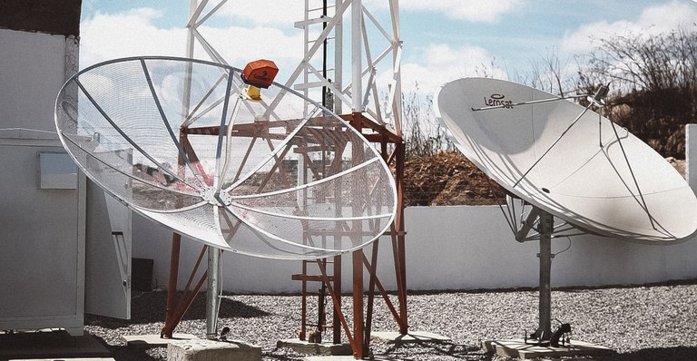 Duas antenas parabólicas instaladas em área externa de estação de telecomunicações representando a substituição pela parabólica digital