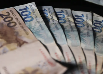 Cédulas de duzentos e cem reais dispostas em formato de leque sobre fundo escuro