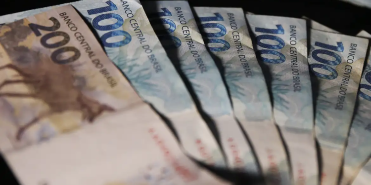 Cédulas de duzentos e cem reais dispostas em formato de leque sobre fundo escuro