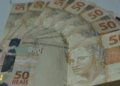 Conjunto de cédulas de cinquenta reais dispostas em leque sobre superfície clara