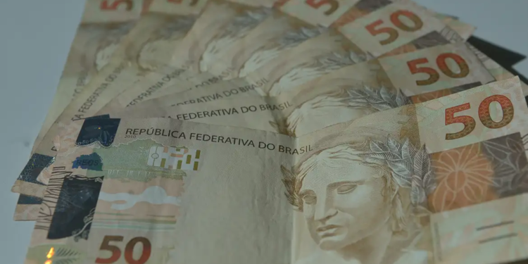 Conjunto de cédulas de cinquenta reais dispostas em leque sobre superfície clara