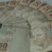 Conjunto de cédulas de cinquenta reais dispostas em leque sobre superfície clara