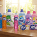 Produtos Ypê enfileirados em bancada de cozinha: detergentes coloridos, amaciantes florais e sabão em barra.