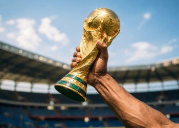 Taça da Copa do Mundo erguida no estádio sob céu azul.
