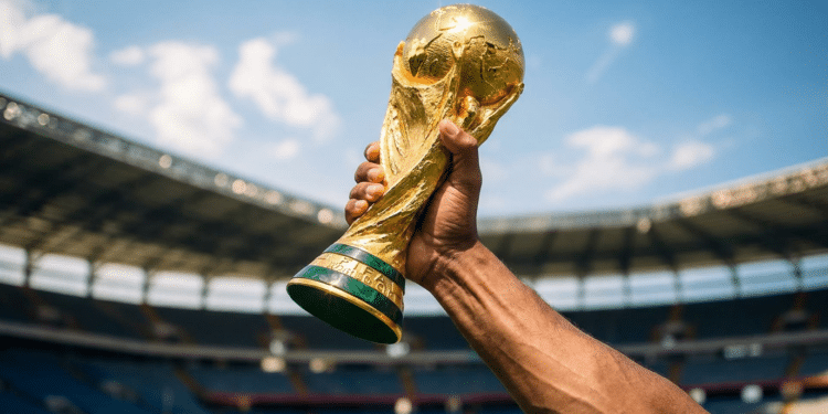 Taça da Copa do Mundo erguida no estádio sob céu azul.