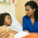 Mãe sentada ao lado da filha doente no hospital.