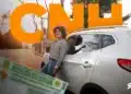 Jovem comemorando ao receber nova CNH ao lado de carro branco, destacando aumento na emissão de carteiras de habilitação.