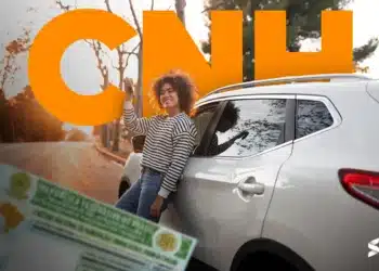 Jovem comemorando ao receber nova CNH ao lado de carro branco, destacando aumento na emissão de carteiras de habilitação.