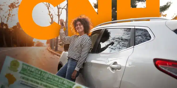 Jovem comemorando ao receber nova CNH ao lado de carro branco, destacando aumento na emissão de carteiras de habilitação.