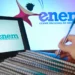 Notebook exibindo logo do Enem, cadernos empilhados e mão segurando caneta em fundo azul com marca do exame
