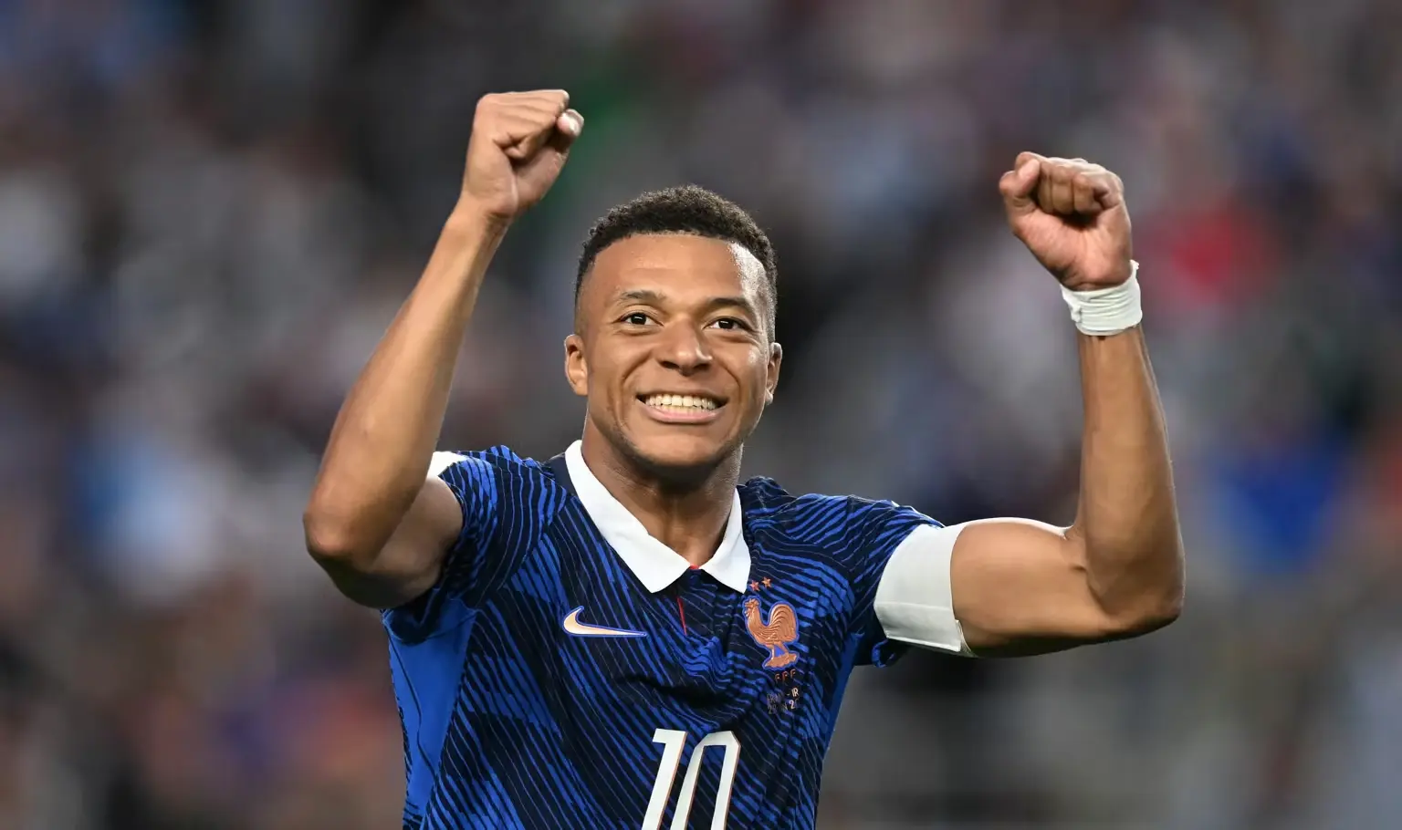 Mbappé Jogador da seleção francesa comemora gol em partida da Copa do Mundo com braços erguidos e expressão de celebração.