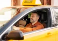 Motorista de táxi dirigindo veículo amarelo com identificação do programa Move Brasil, voltado à renovação da frota de transporte de passageiros.
