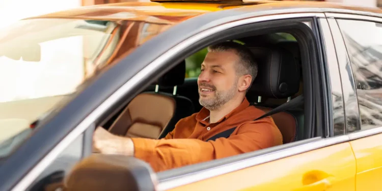 Motorista de táxi dirigindo veículo amarelo com identificação do programa Move Brasil, voltado à renovação da frota de transporte de passageiros.